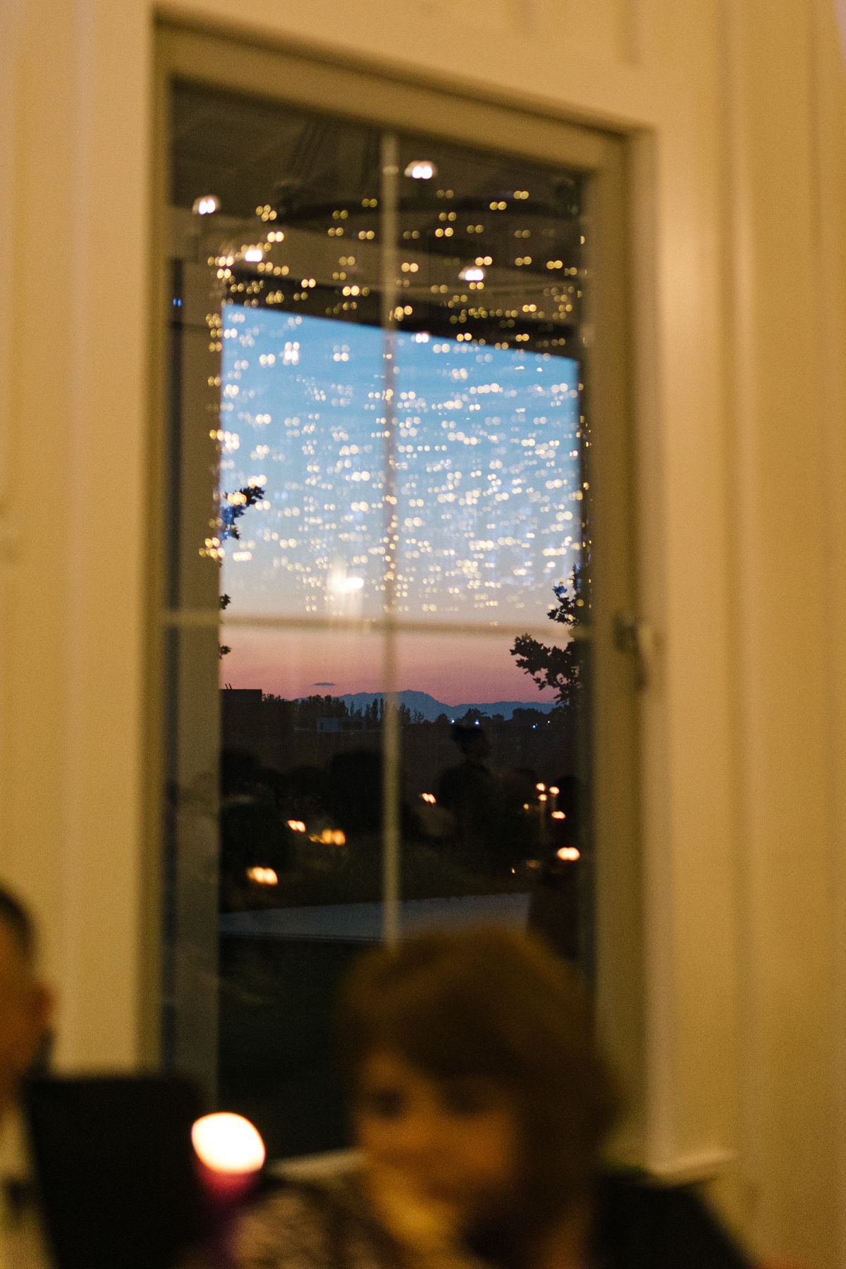 Sunset view through windows with hanging fairy lights creating a magical atmosphere.