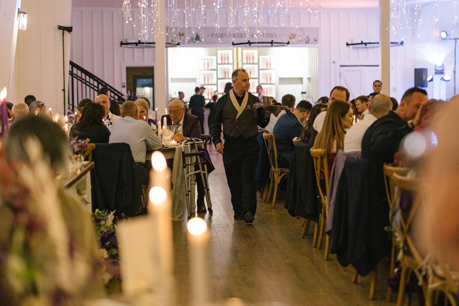 Formal event space filled with guests mingling under decorative lighting.