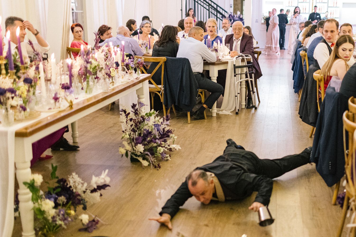 Reception venue with guests dancing and celebrating on wooden floors under decorative lighting.
