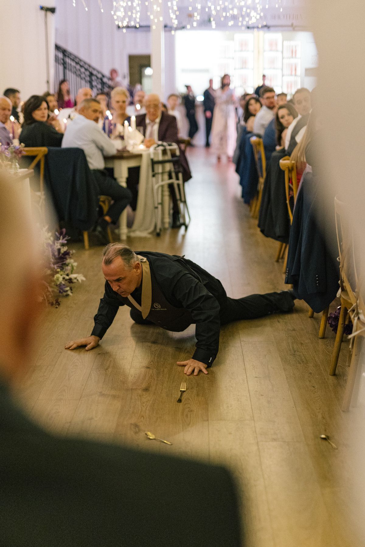 Wedding guest performs breakdancing moves on the dance floor during reception.