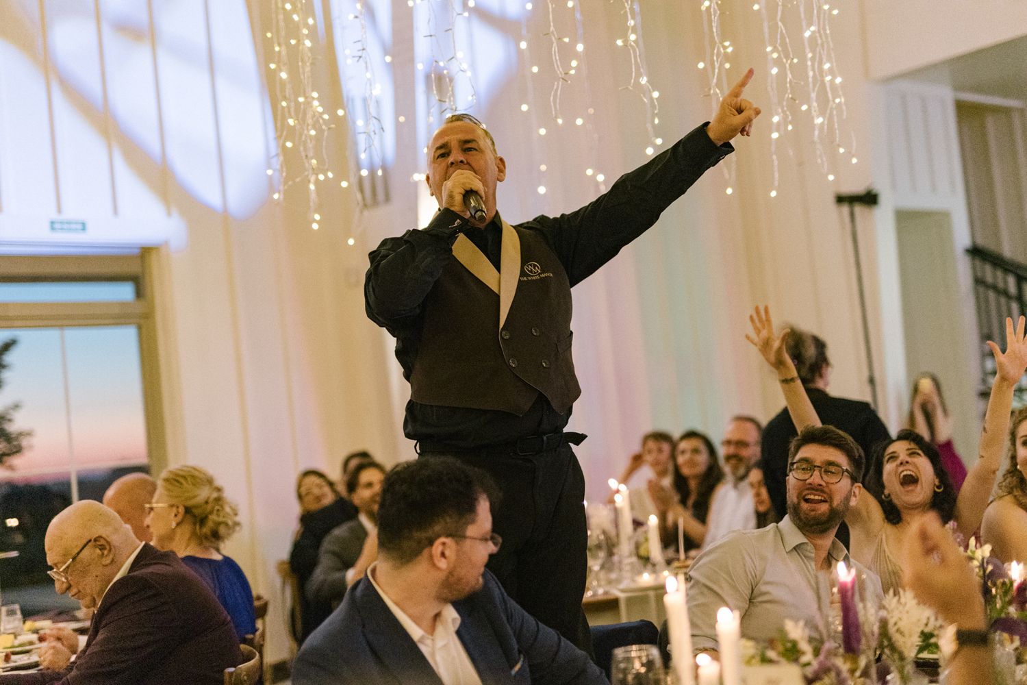 Enthusiastic guests cheering with raised hands at an elegant wedding reception.