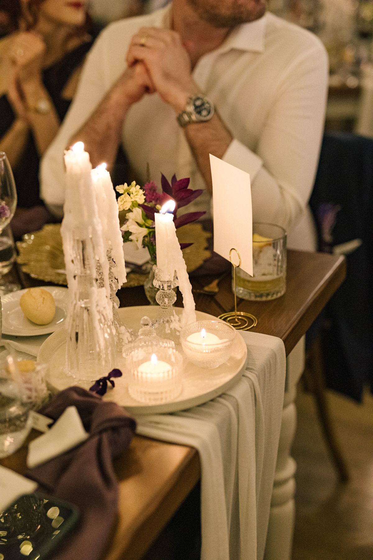 Candlelit wedding reception table with white taper candles and elegant place settings.