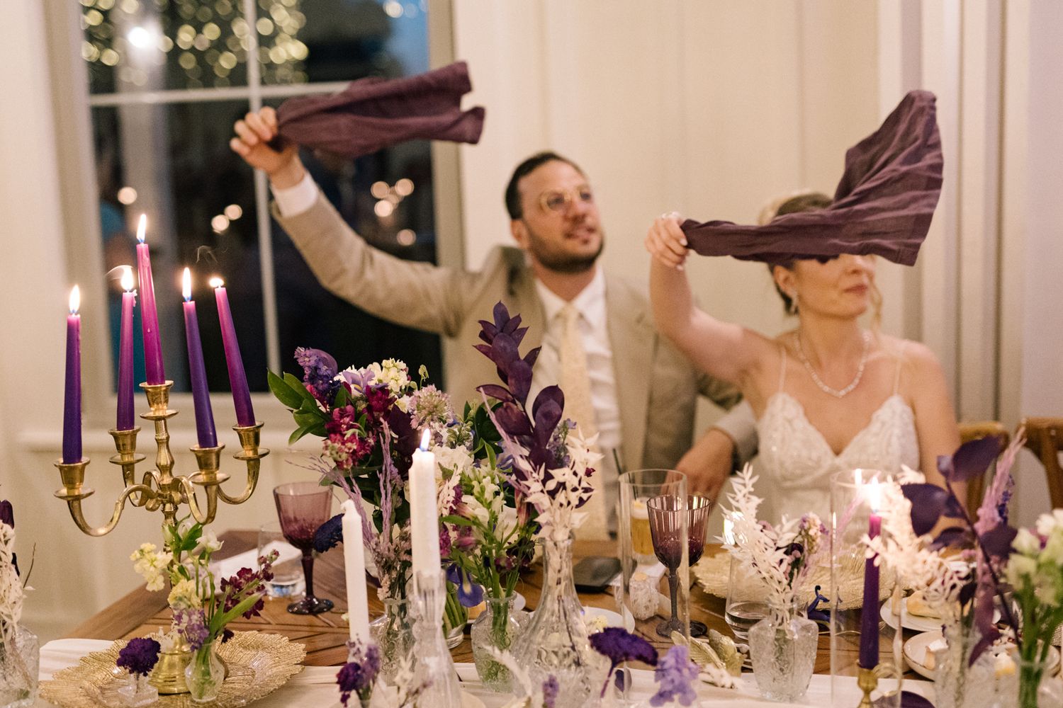 Elegant wedding reception table decorated with purple candles and floral centerpieces.