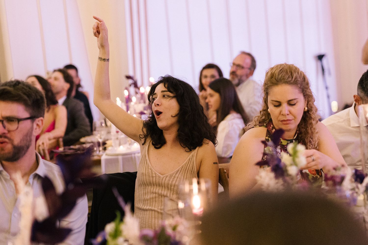 Enthusiastic party guests celebrating at an elegant indoor event with decorative table settings.