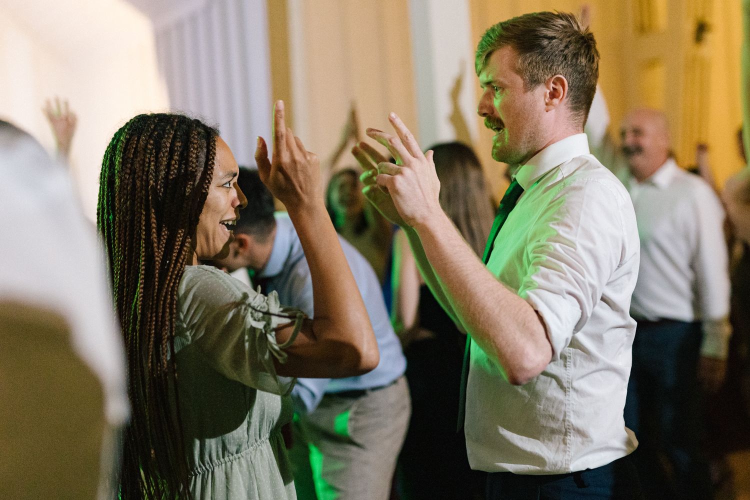 Two party guests high-fiving while dancing at a festive indoor celebration.