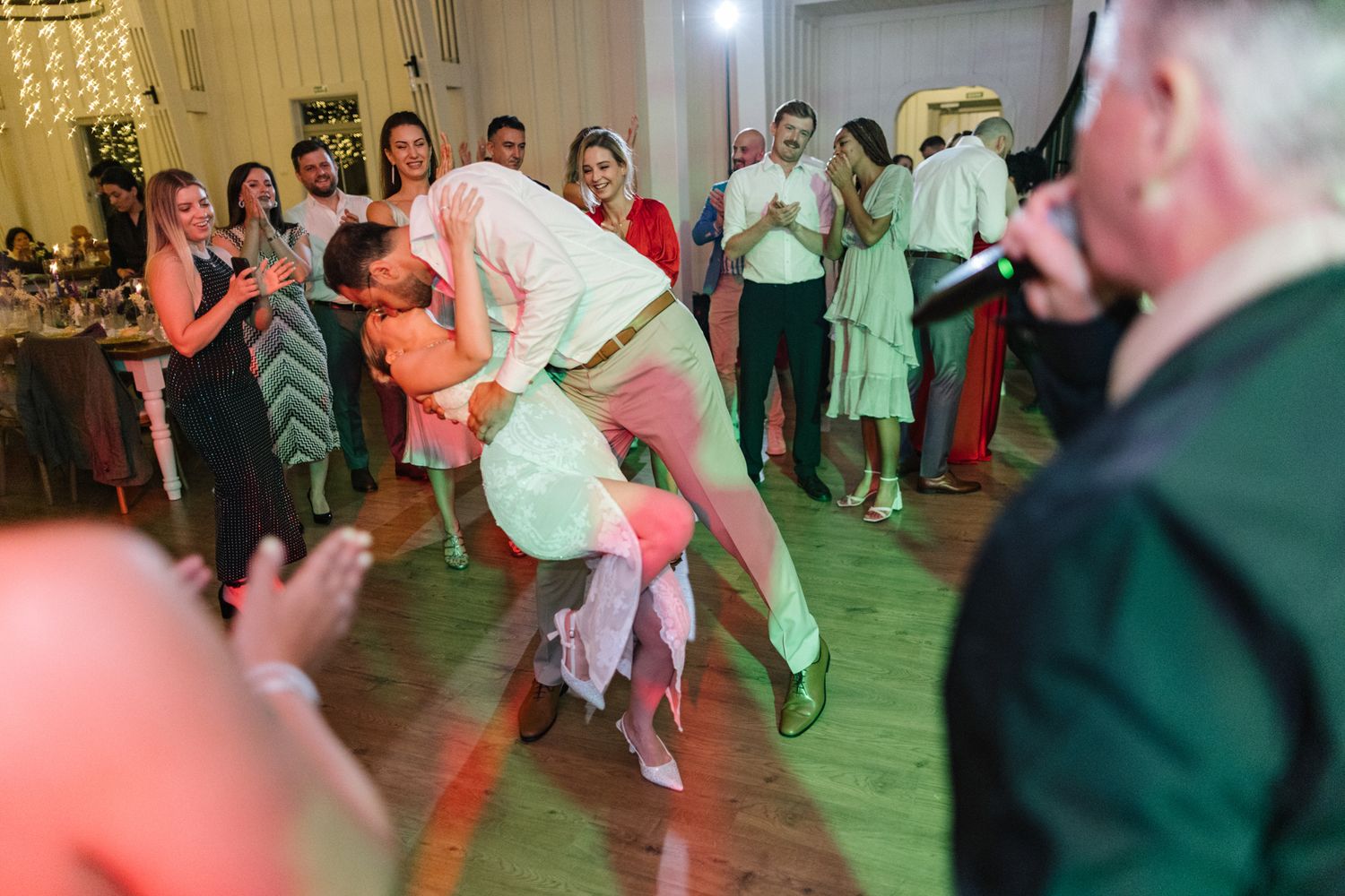 Energetic dancers performing dynamic moves on a wooden dance floor at a celebration.
