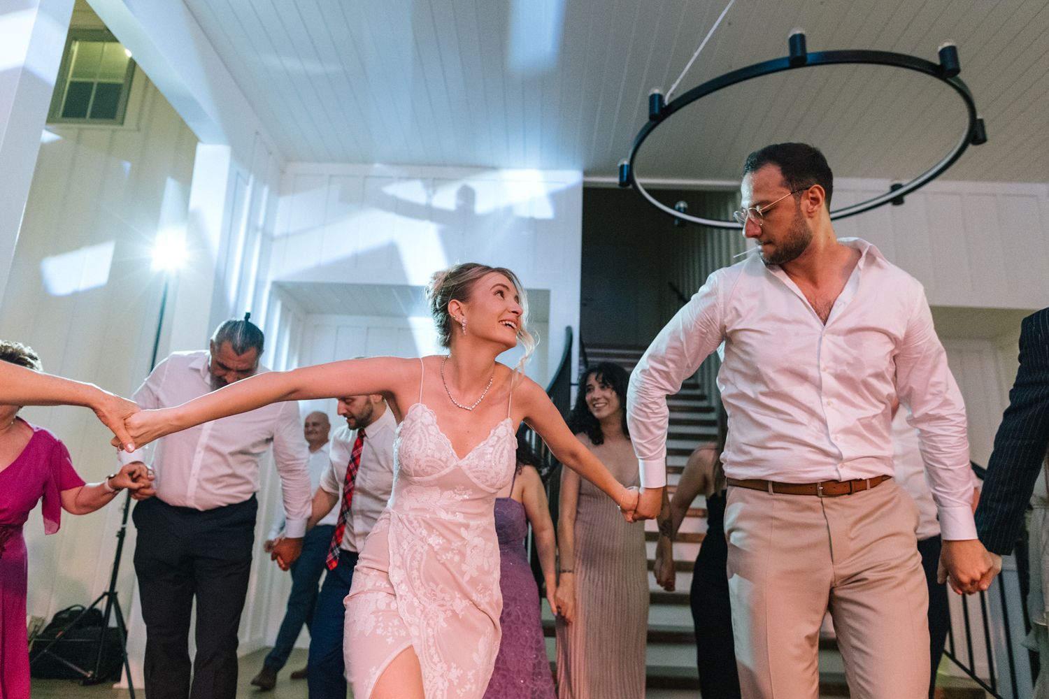 Couples dancing and twirling on a wooden floor during an indoor celebration.
