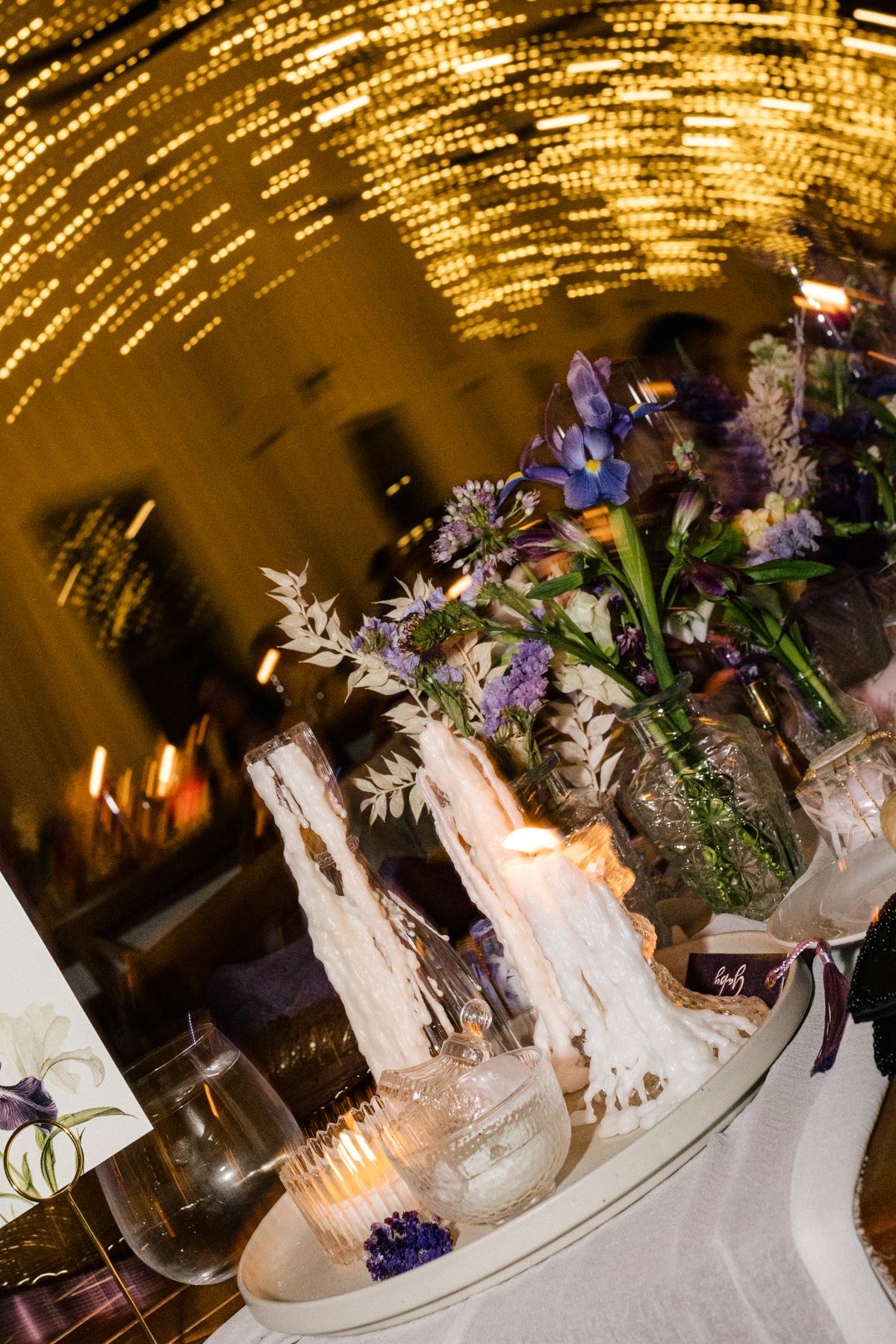 Elegant wedding table decor with floral arrangements under dramatic golden lighting.