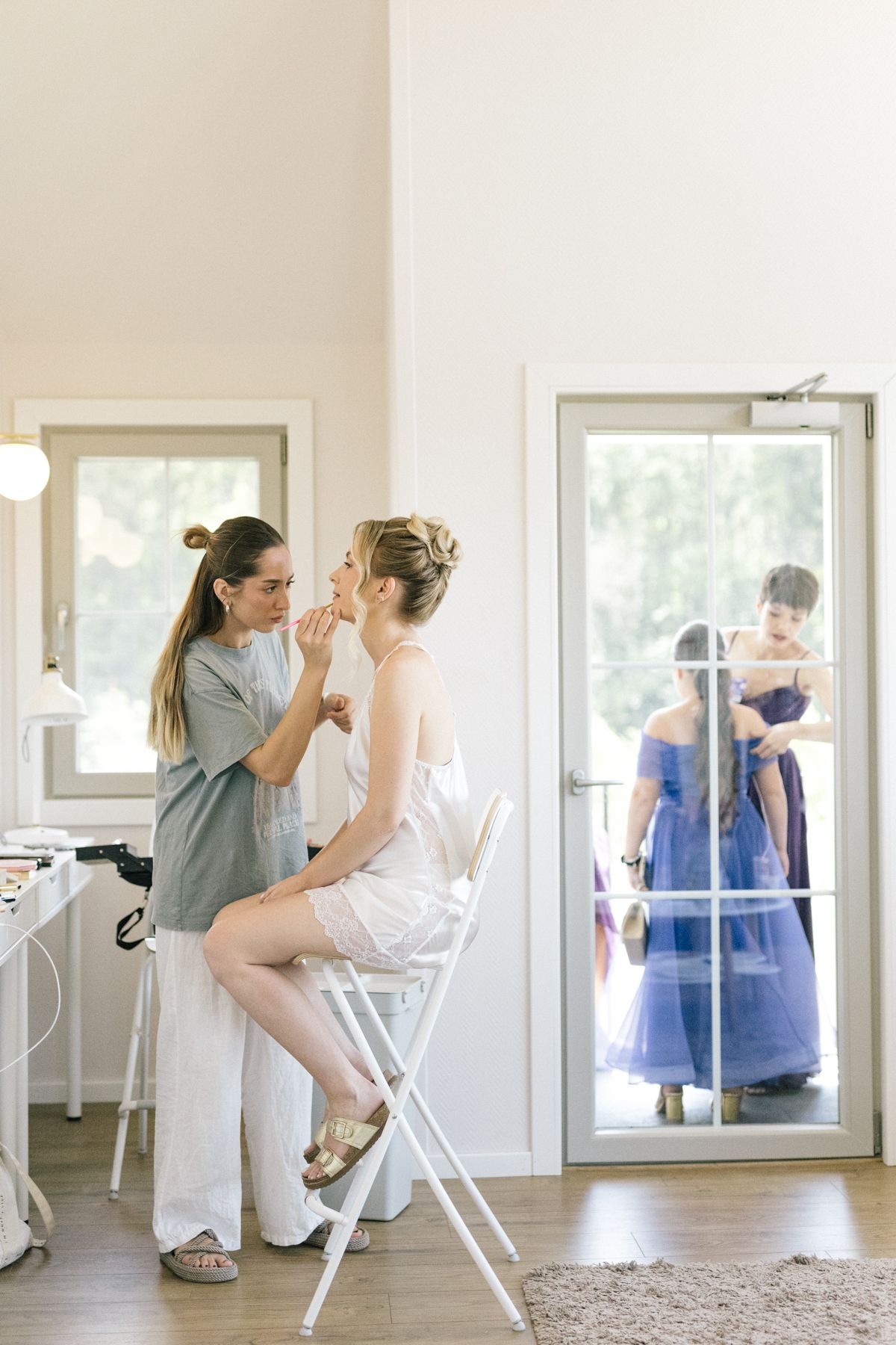 Wedding preparation scene in a bright room with mirrors and chairs.