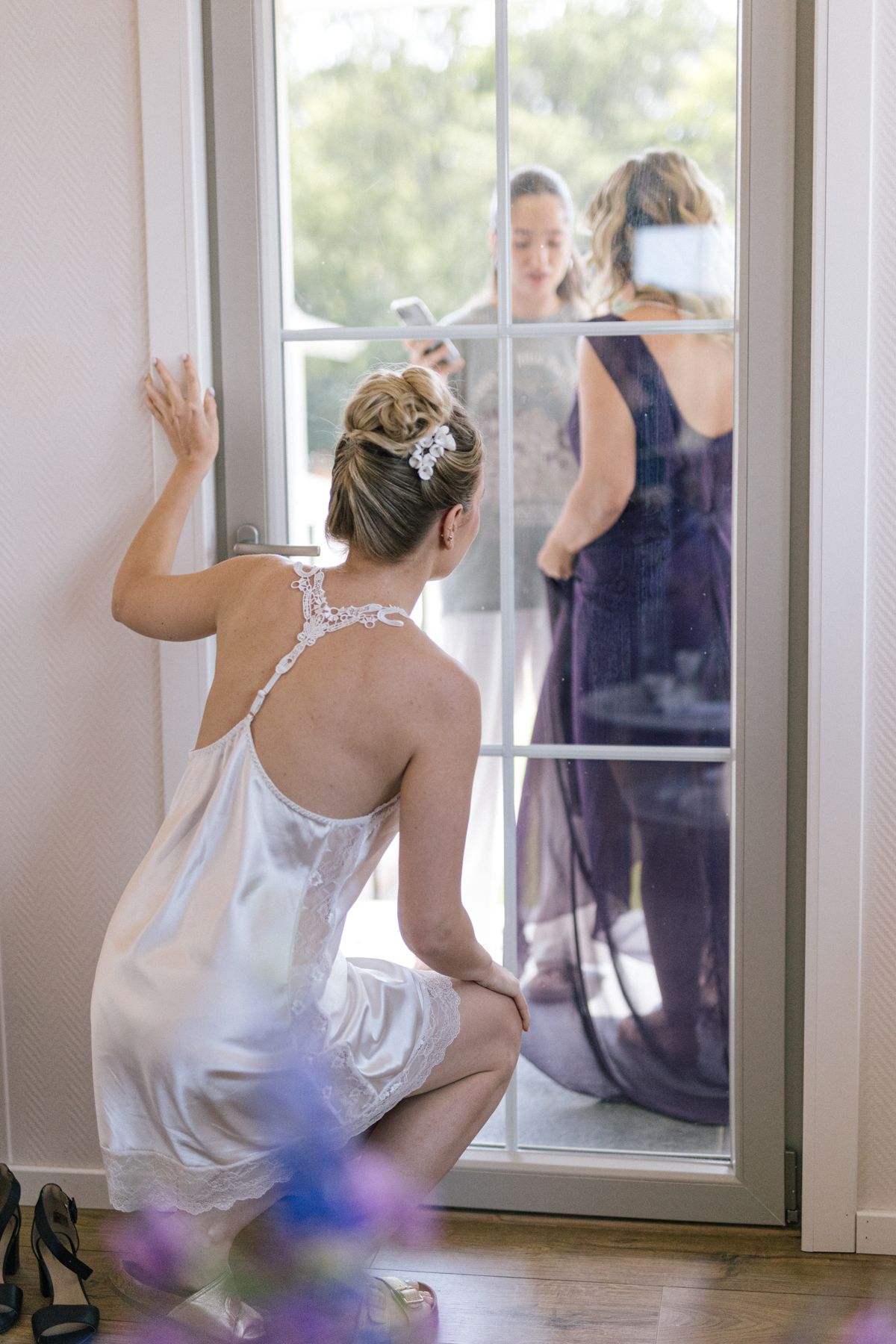 Bright sunlit room with wedding preparations reflected in window panes.