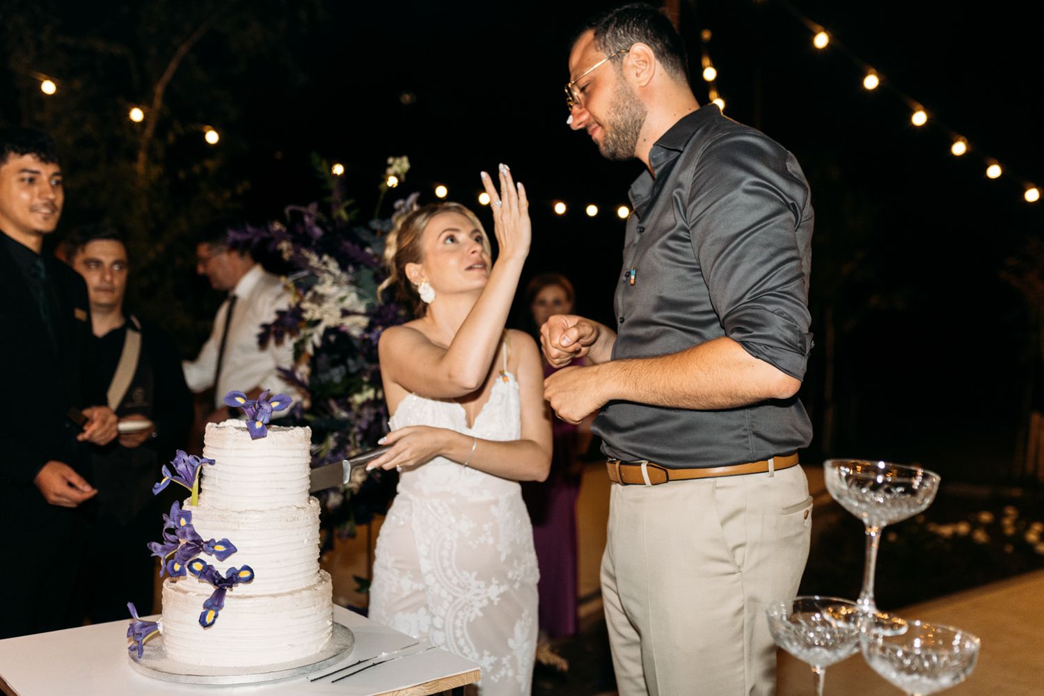 Wedding celebration at night with string lights and cake display.