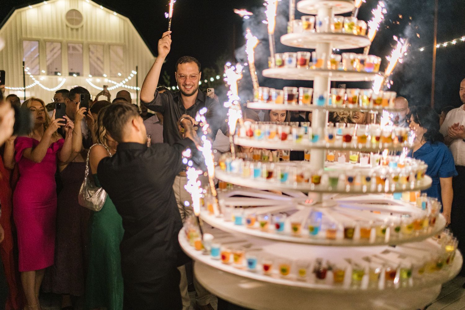 Illuminated tiered dessert display glowing at nighttime wedding celebration.