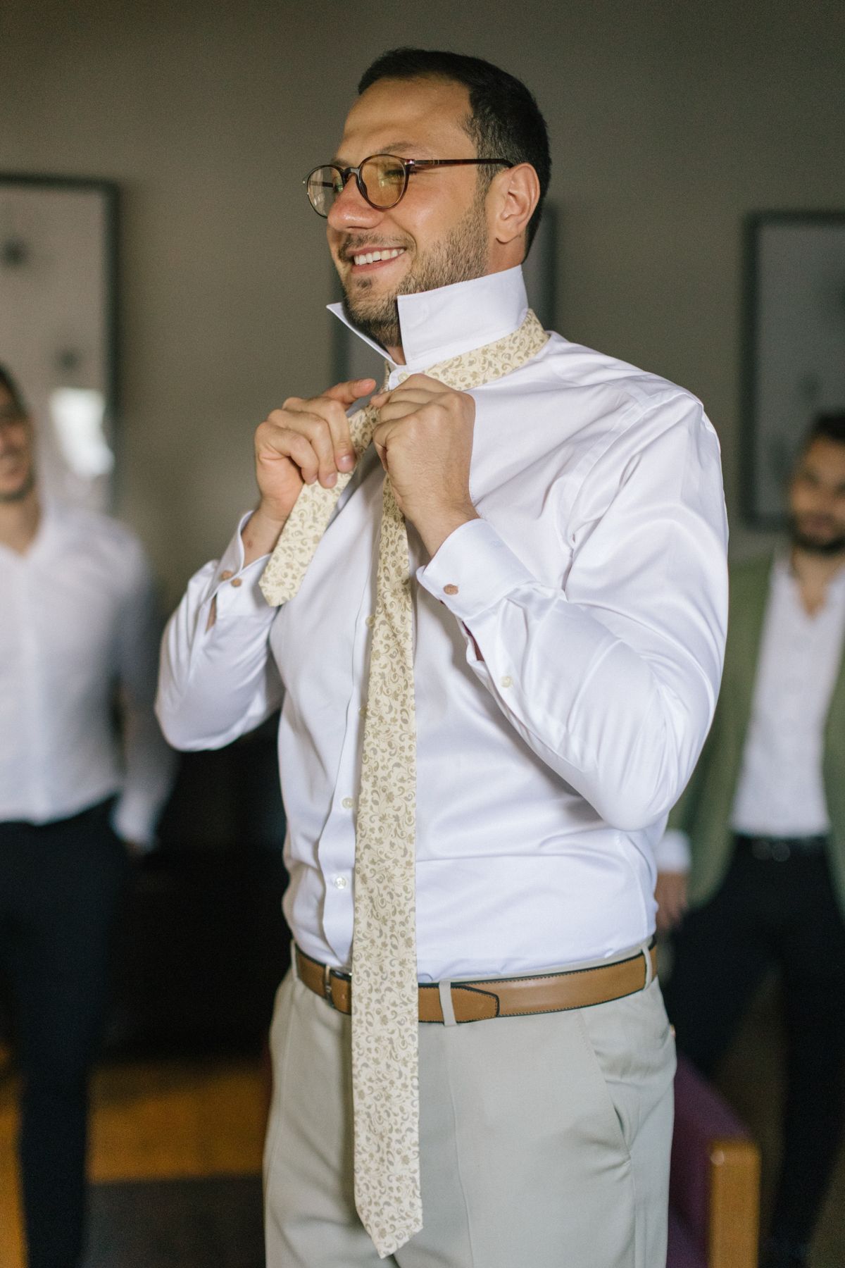 Person adjusting formal attire while wearing a patterned tie and white dress shirt.