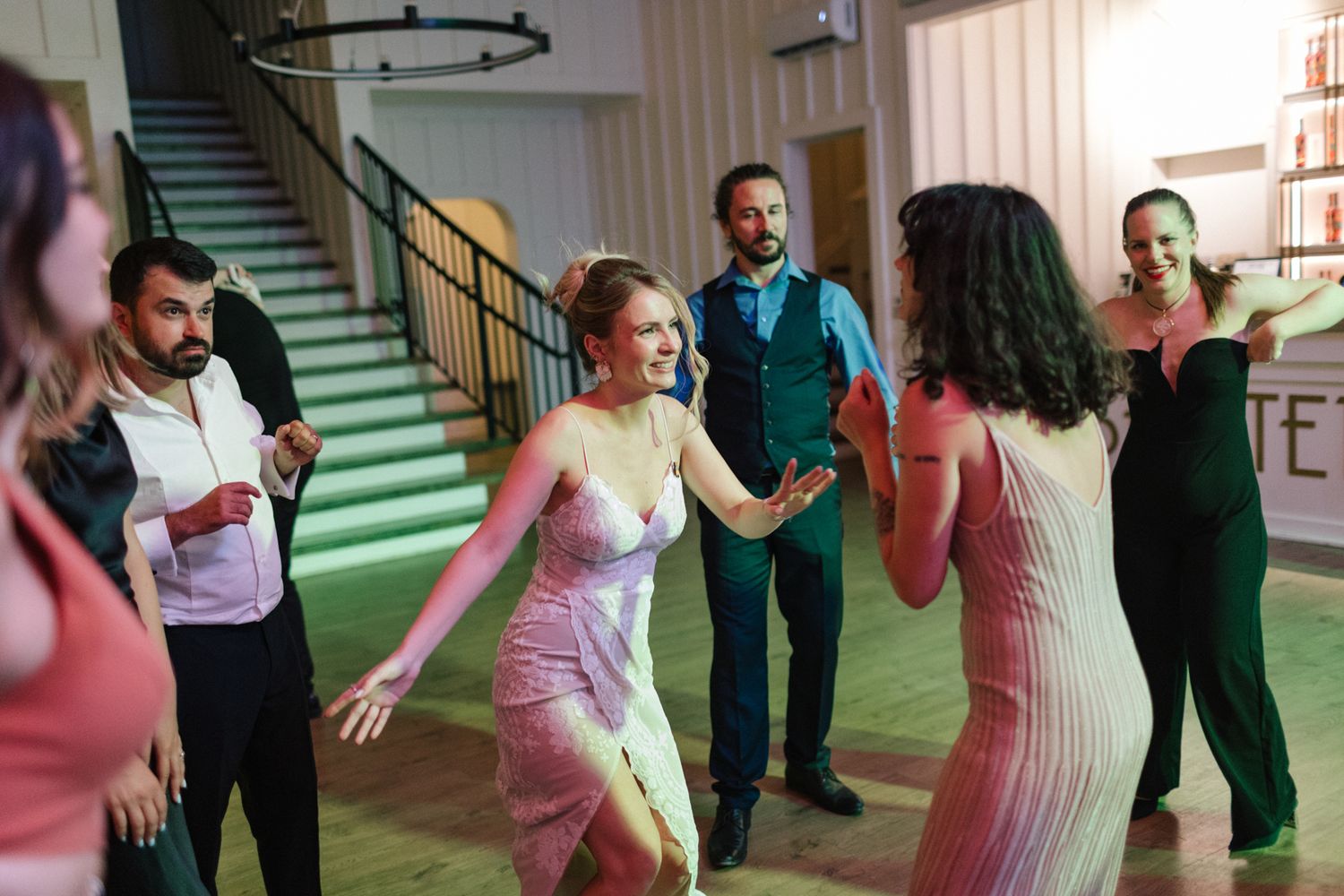 Wedding guests dancing and celebrating on indoor dance floor.