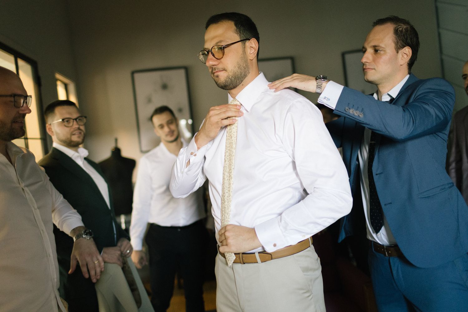 Men in formal attire socializing in modern indoor space.