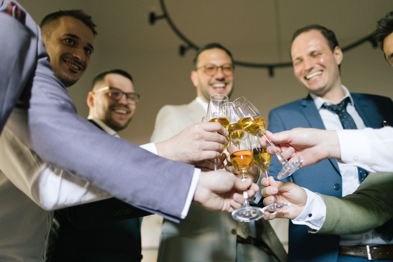 Groomsmen toasting with beer glasses in a celebratory moment.