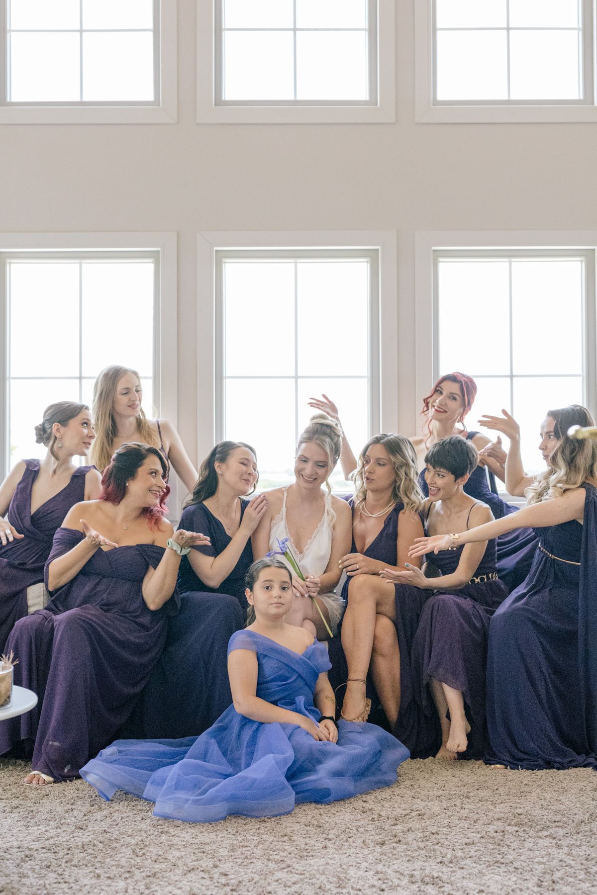 Wedding party bridesmaids relaxing and laughing together in formal dresses.