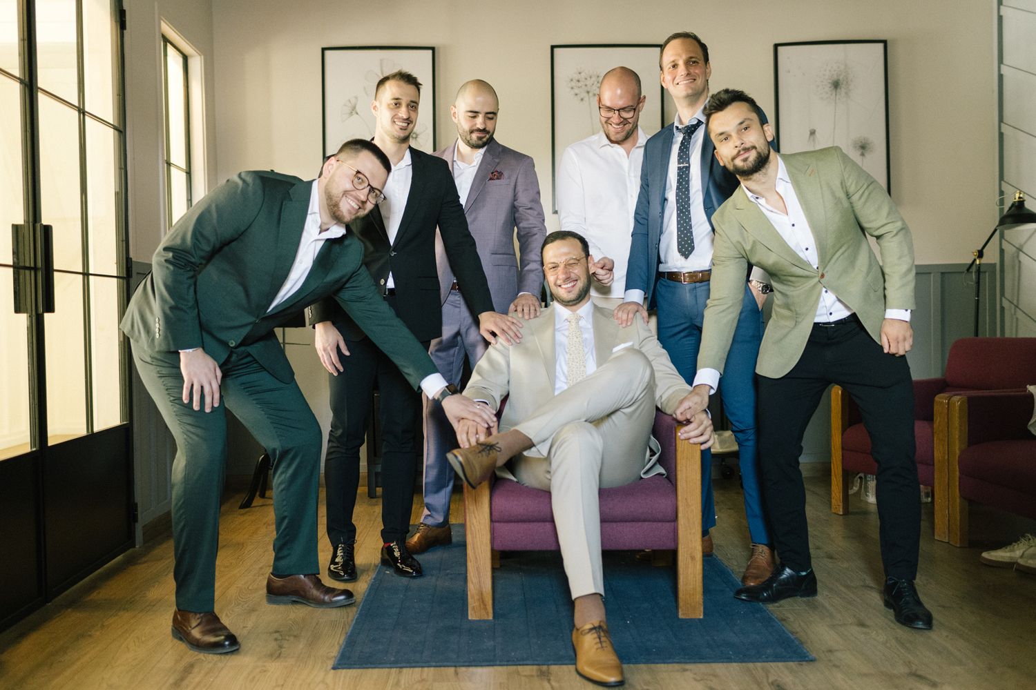 Groomsmen in suits posing playfully for a group photo.