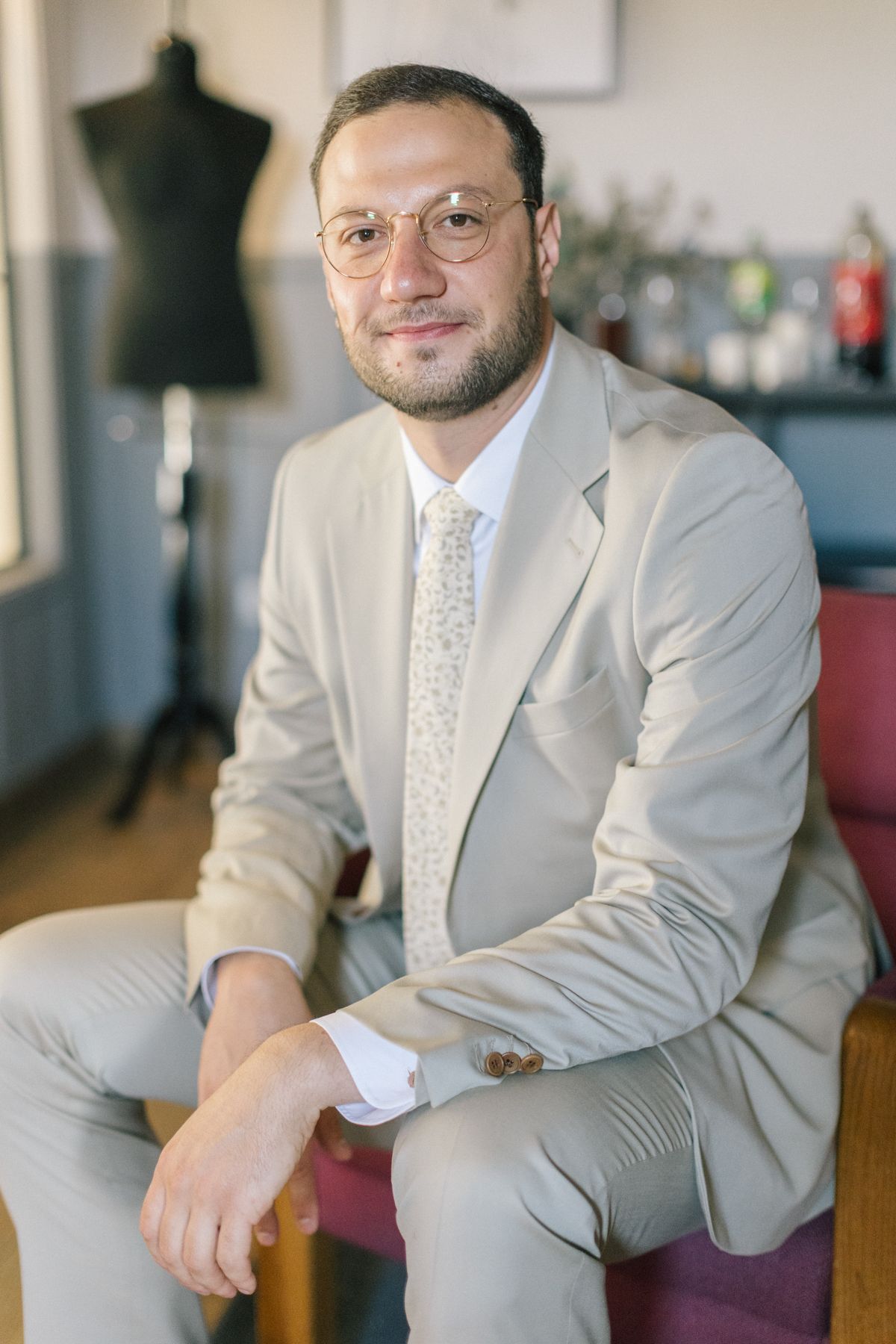 Groom in light gray suit sitting casually for portrait photos.