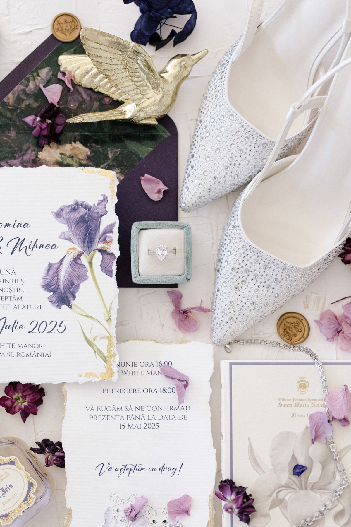 Flat lay of wedding invitations with purple iris illustrations and gold wax seals.
