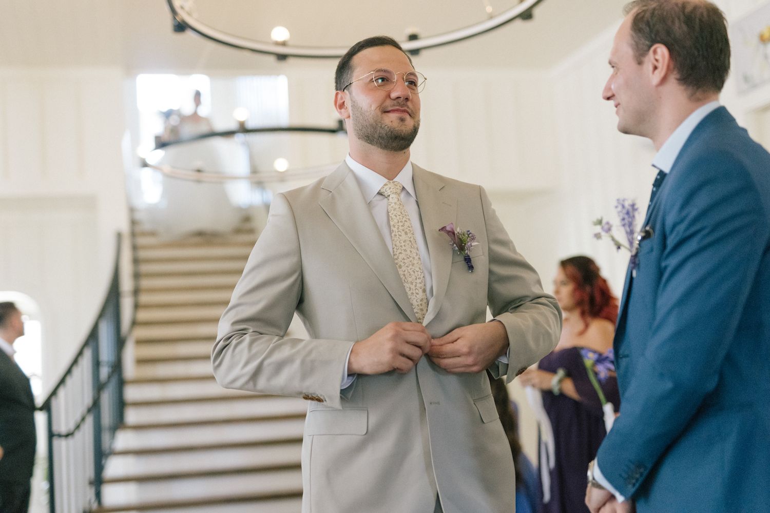 Wedding party members in navy and beige attire gather for formal photos in an elegant venue.