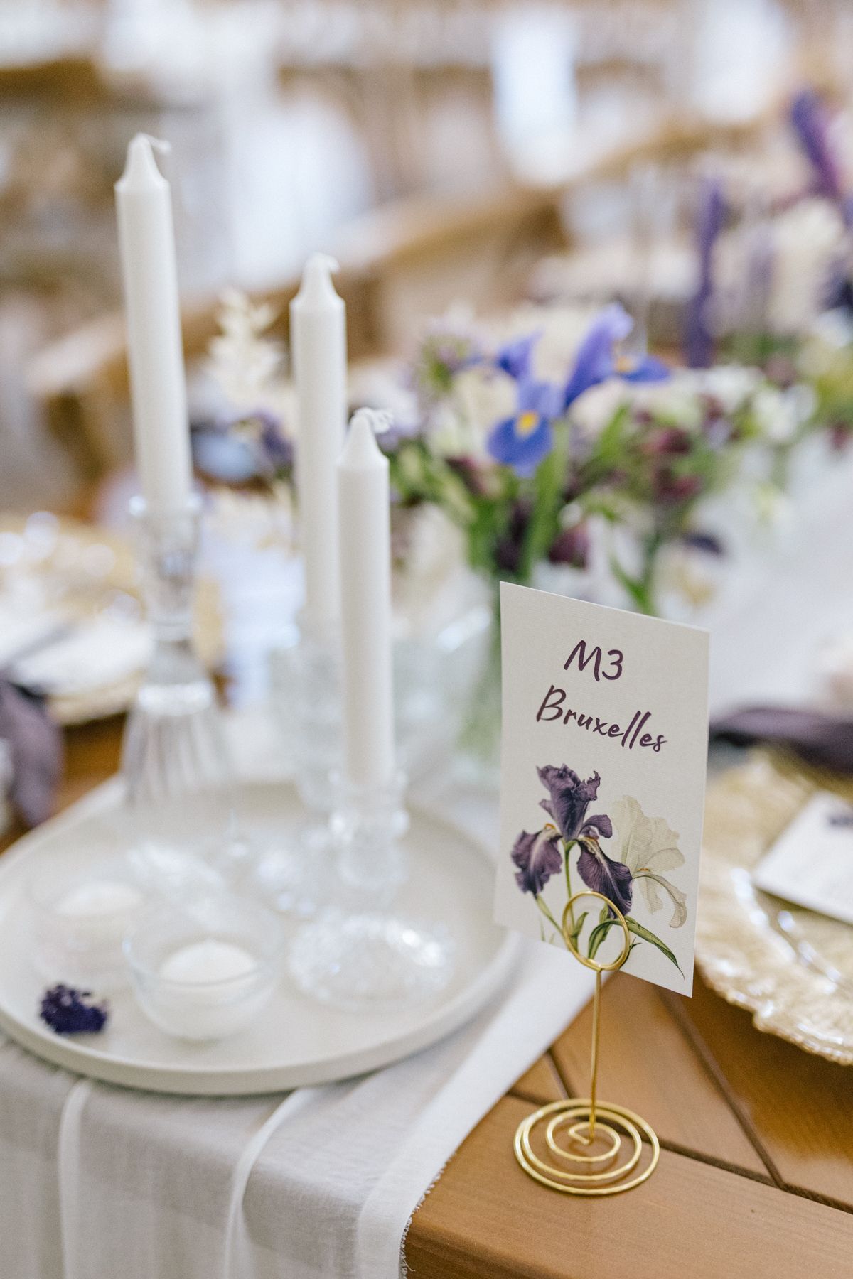 White table settings with gold accents and purple place cards for wedding reception.
