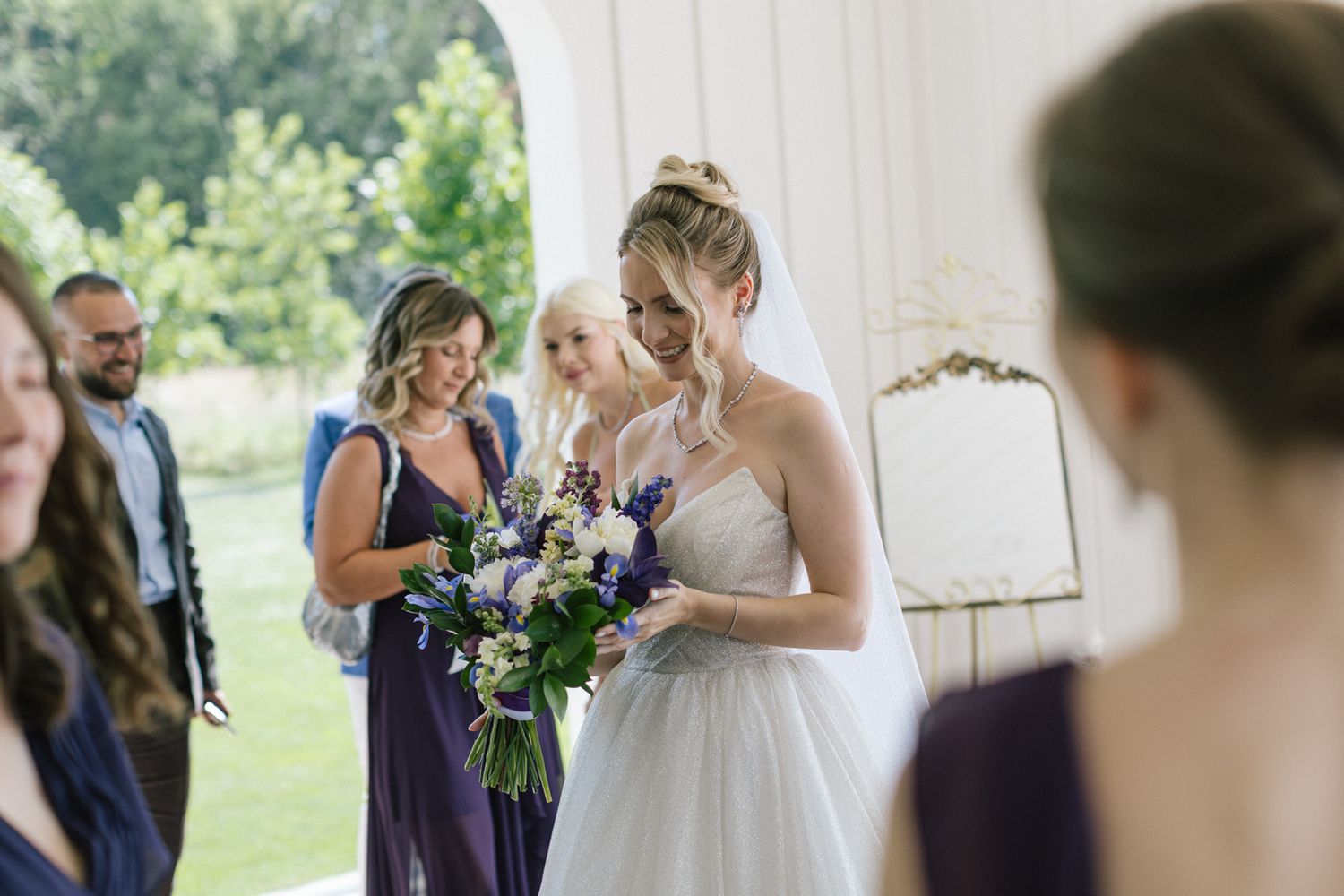 A wedding ceremony moment with attendants in purple dresses holding bouquets.