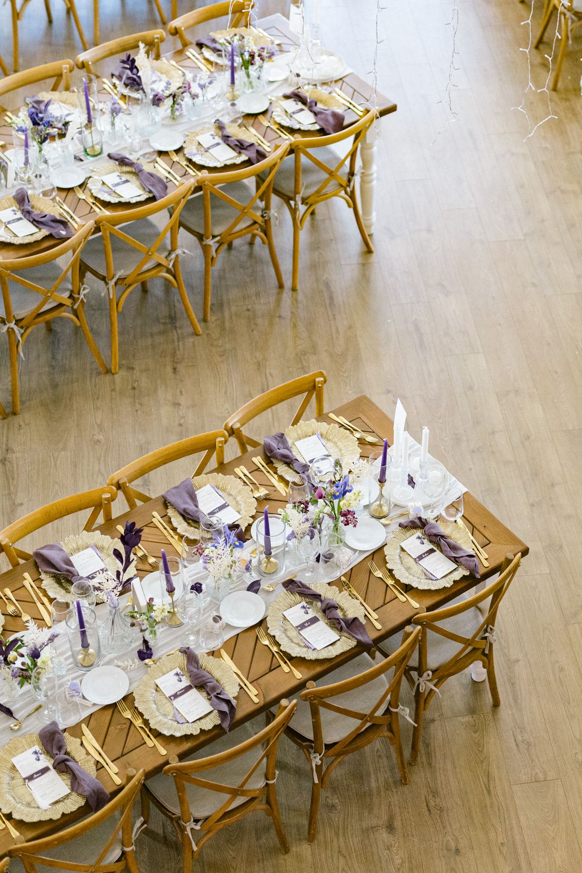 Overhead view of elegant wedding reception tables with gold chairs and purple accents.