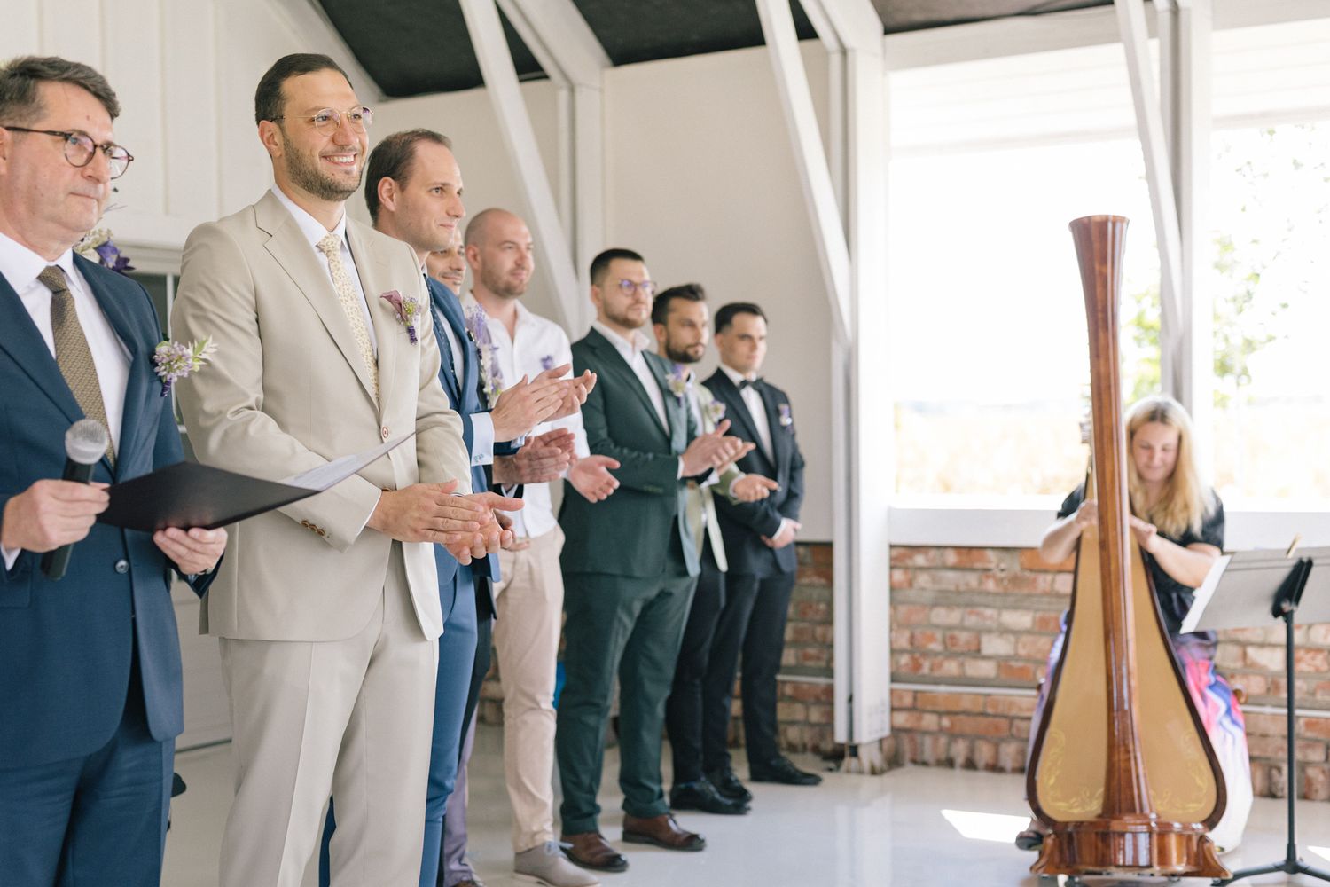 Wedding party members stand in a line during ceremony with a decorative harp visible.
