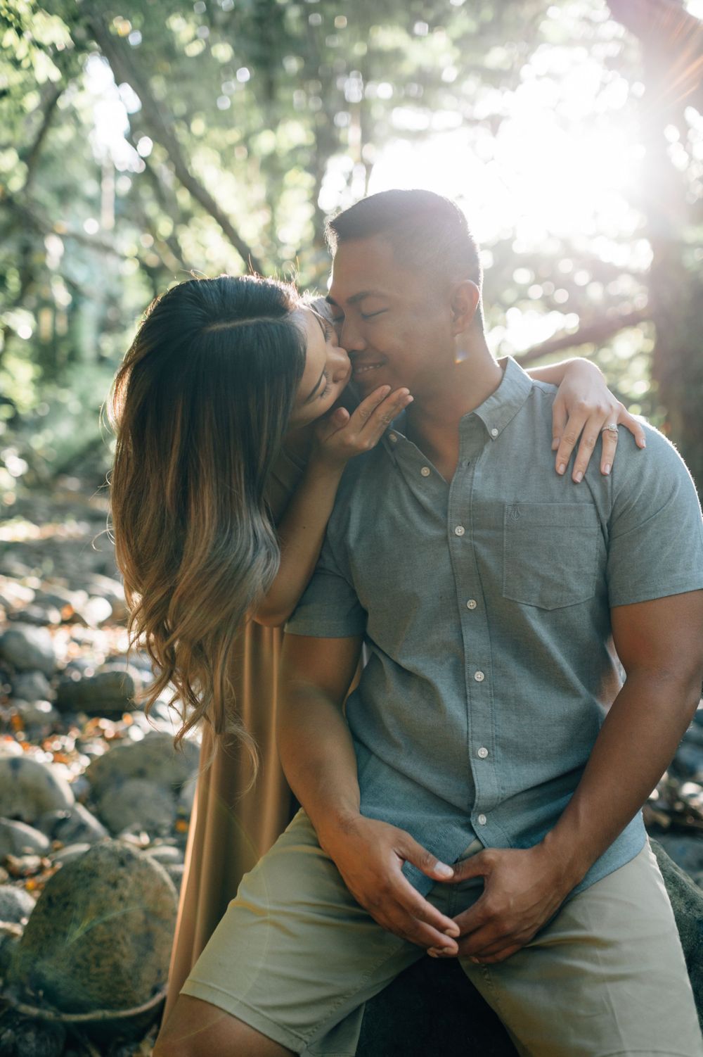 Two people share tender moments while sitting together in dappled sunlight.