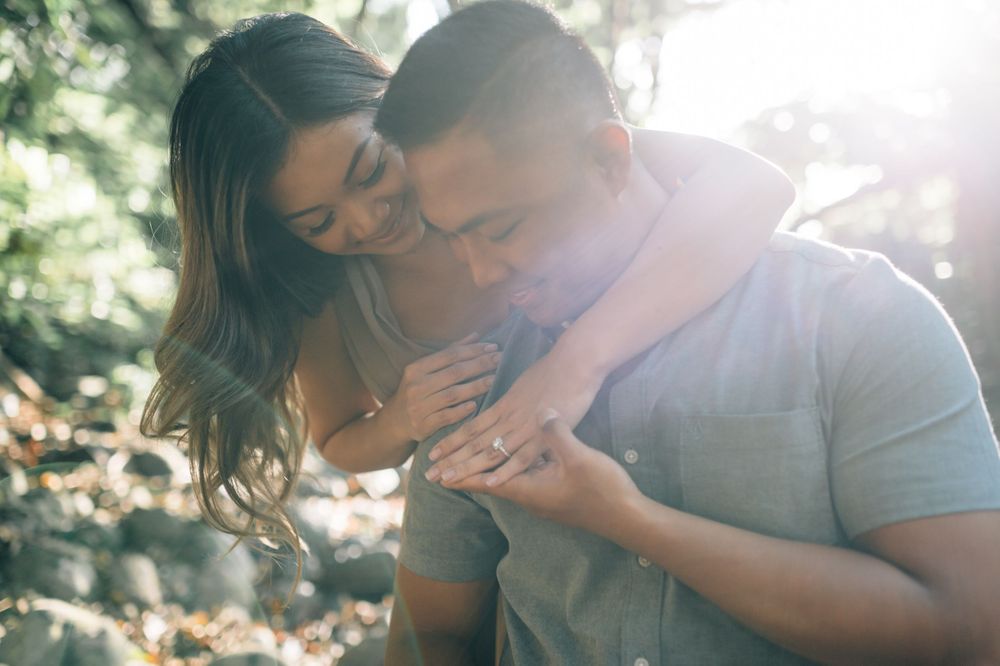 A couple embraces and laughs together in dappled sunlight.
