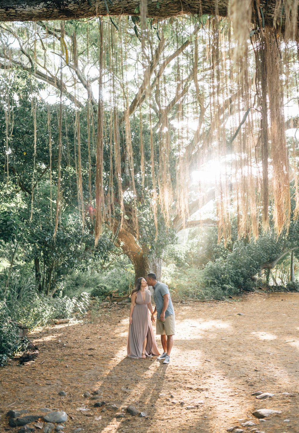 A couple enjoys a romantic moment on a tree-lined dirt path.