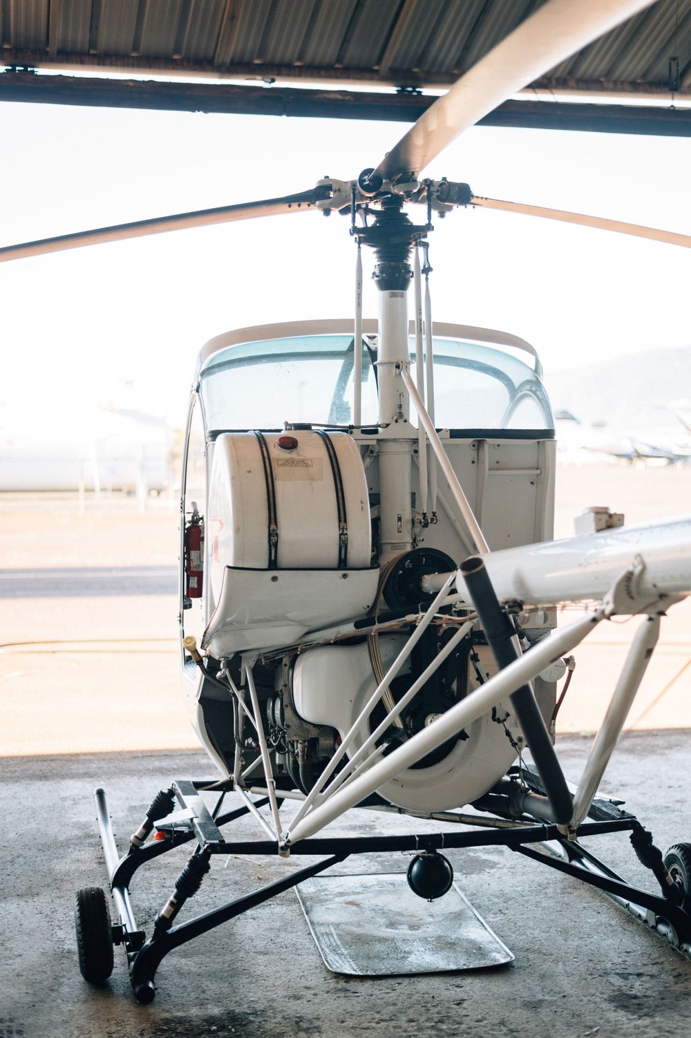 Side view of a white helicopter's landing skids and fuselage on concrete ground.