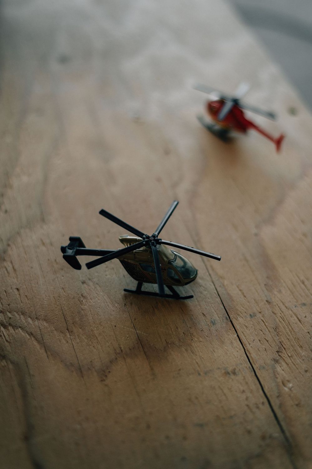 Small toy model military helicopters arranged on a wooden surface.