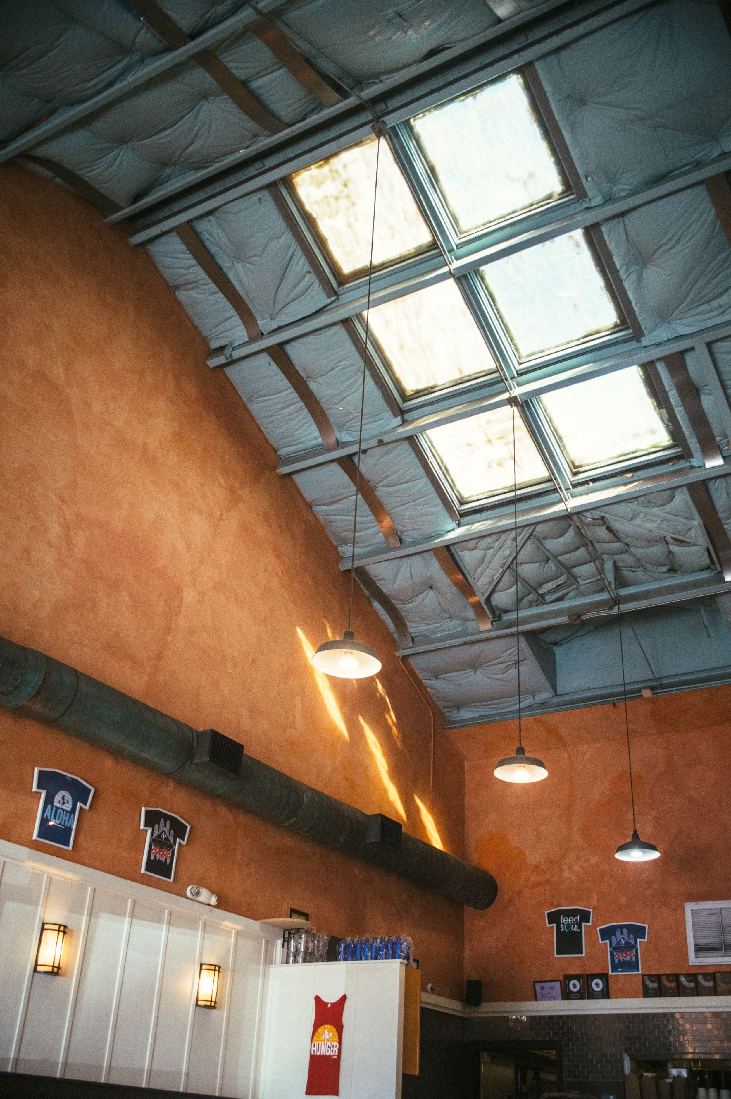 Modern restaurant ceiling with skylights and industrial lighting design.