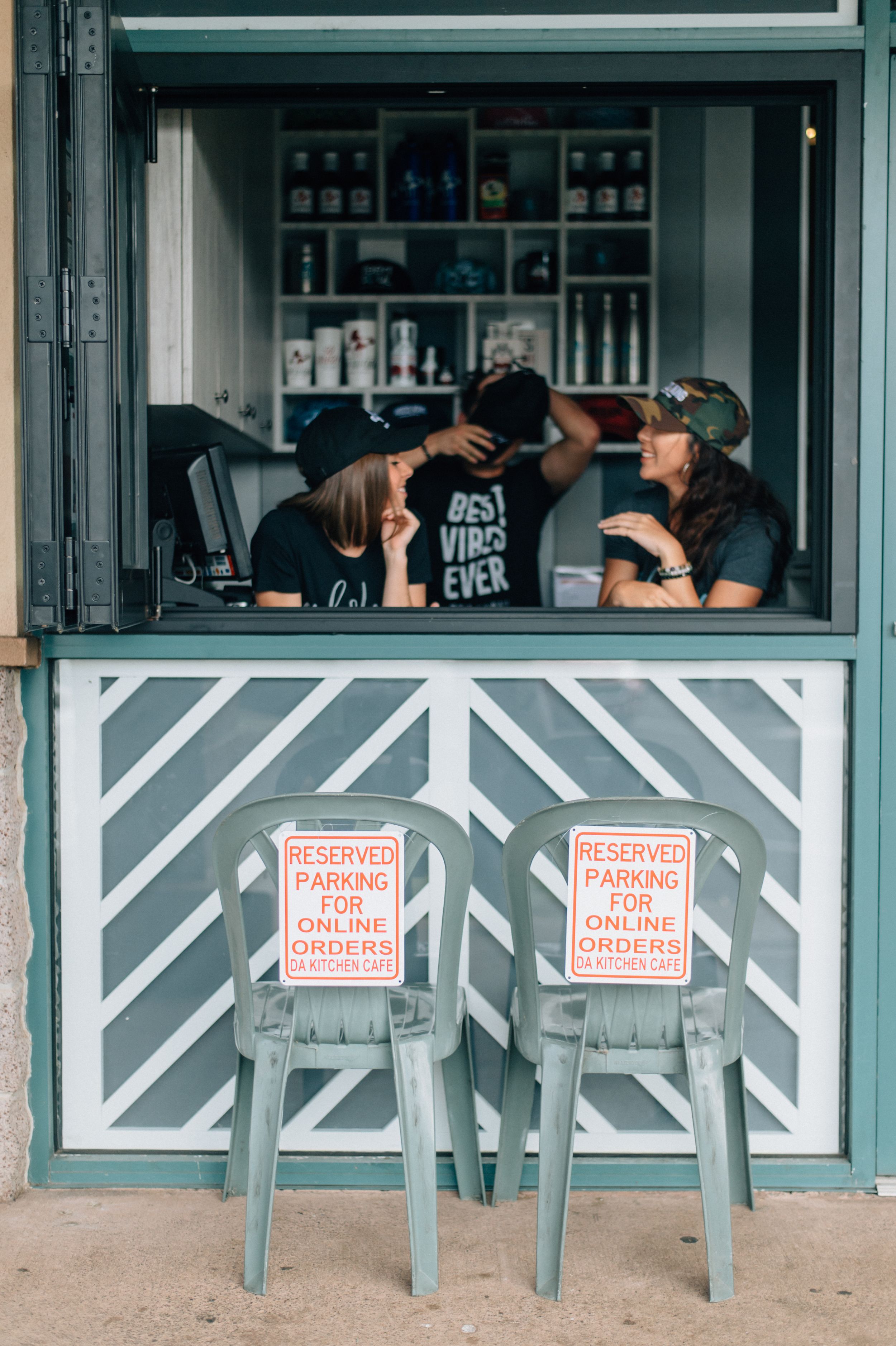 People seated at outdoor counter with reserved parking signs visible below.
