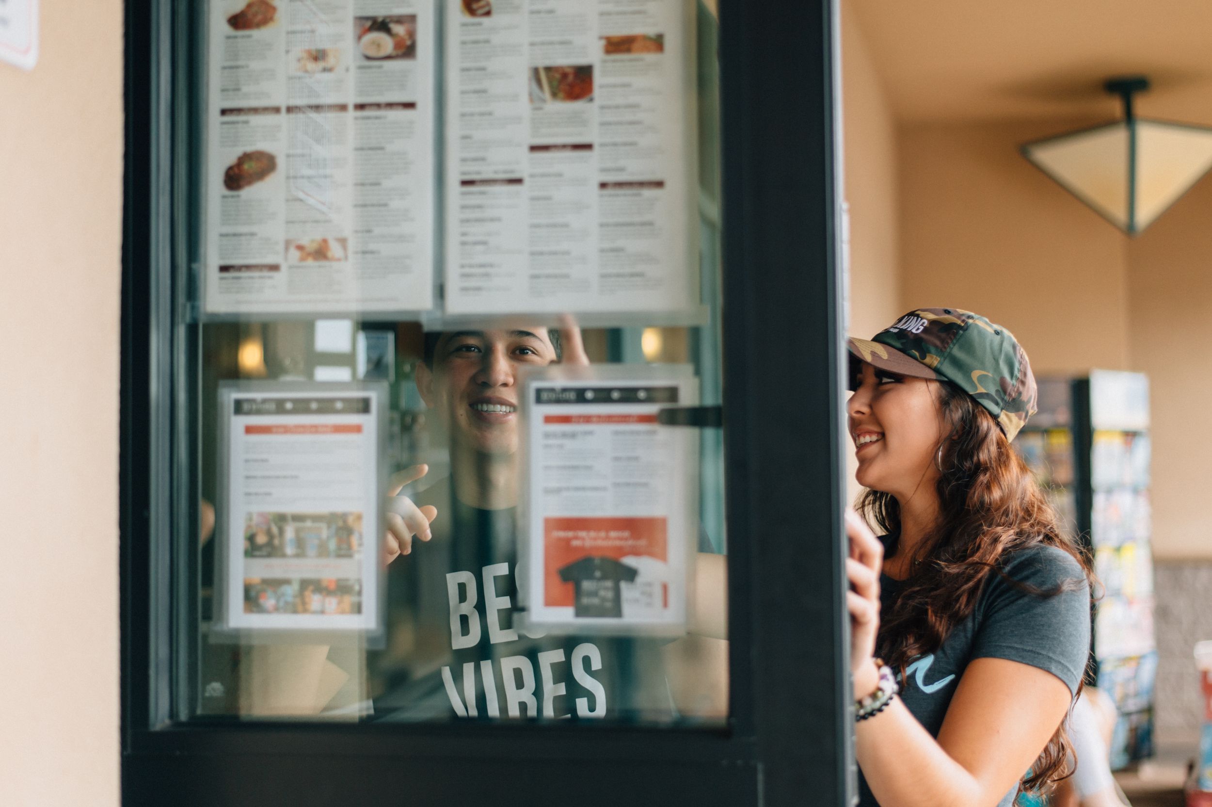 Restaurant menu board with 'Be Vibes' text visible through glass display.