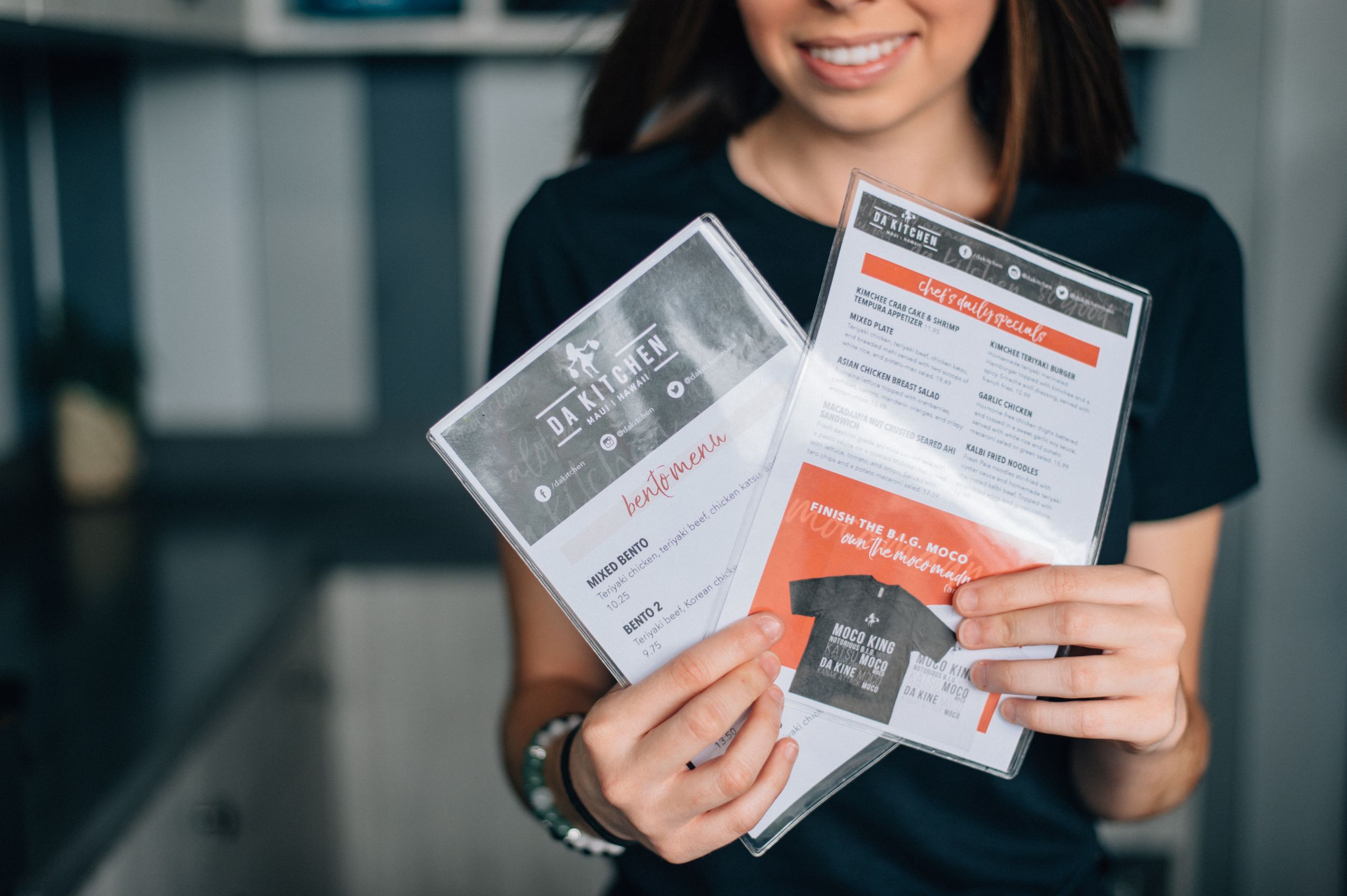 Staff member holding restaurant menus and promotional materials.