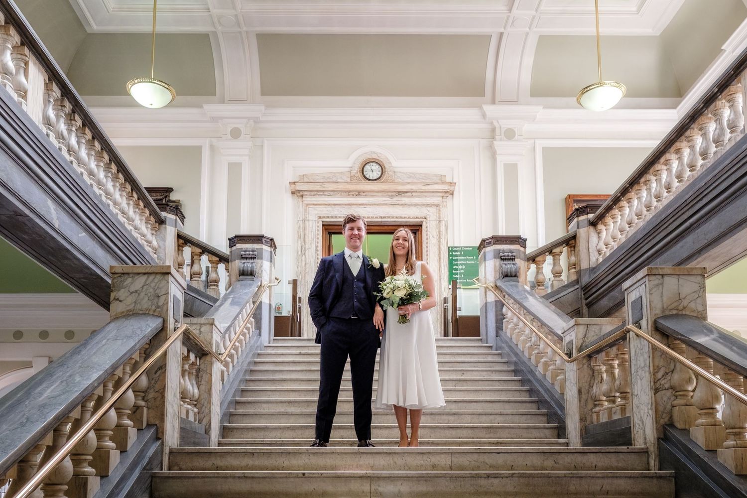Elegant grand staircase in Islington Town Hall interior with white walls and ornate wooden railings.