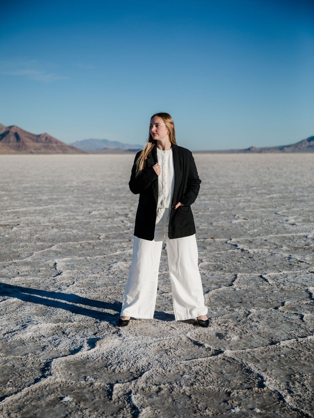 Artistic fashion portraits on cracked salt flats with mountains in the background.