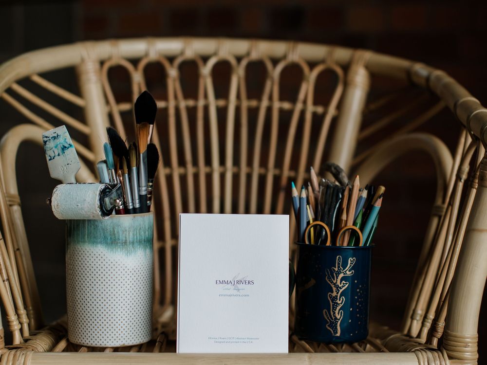 Organized desk setup with art supplies and office tools against a dark background.