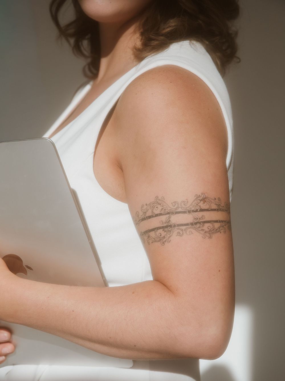 Detail shots showing an arm with a delicate tattoo while wearing a sleeveless white top.