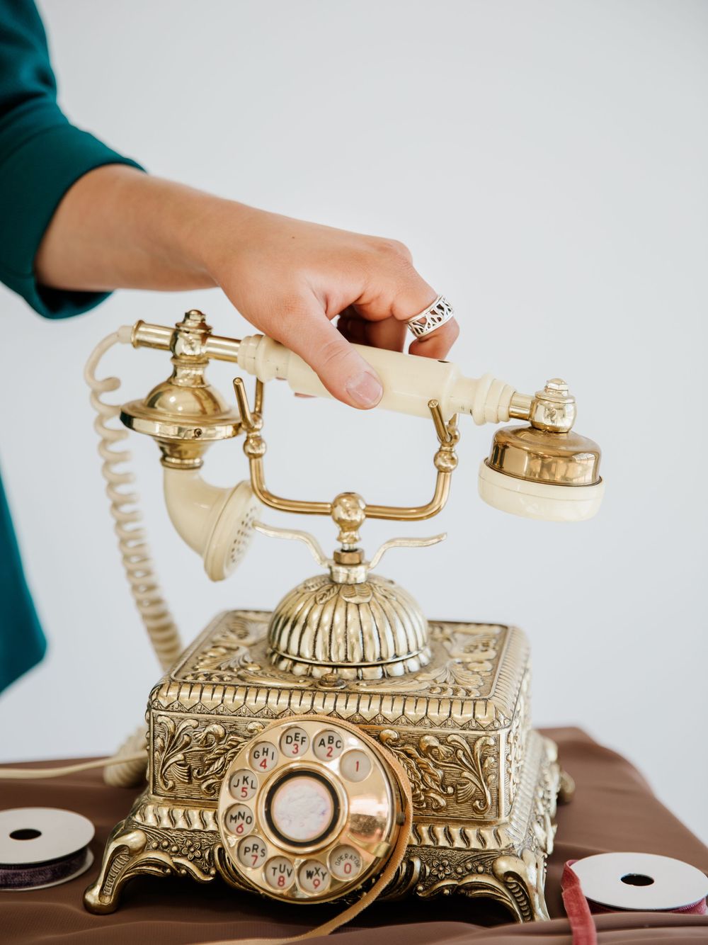 Close-up shots of ornate gold vintage telephone on brown table surface.