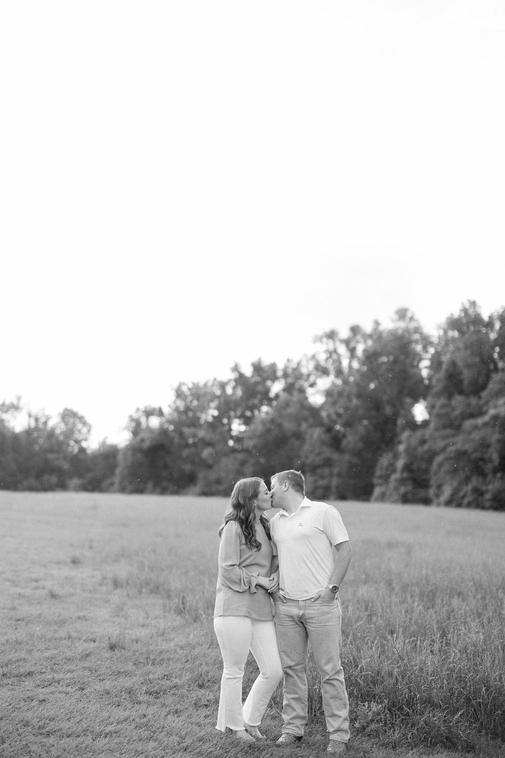 A couple walking together through a scenic meadow in black and white photography.
