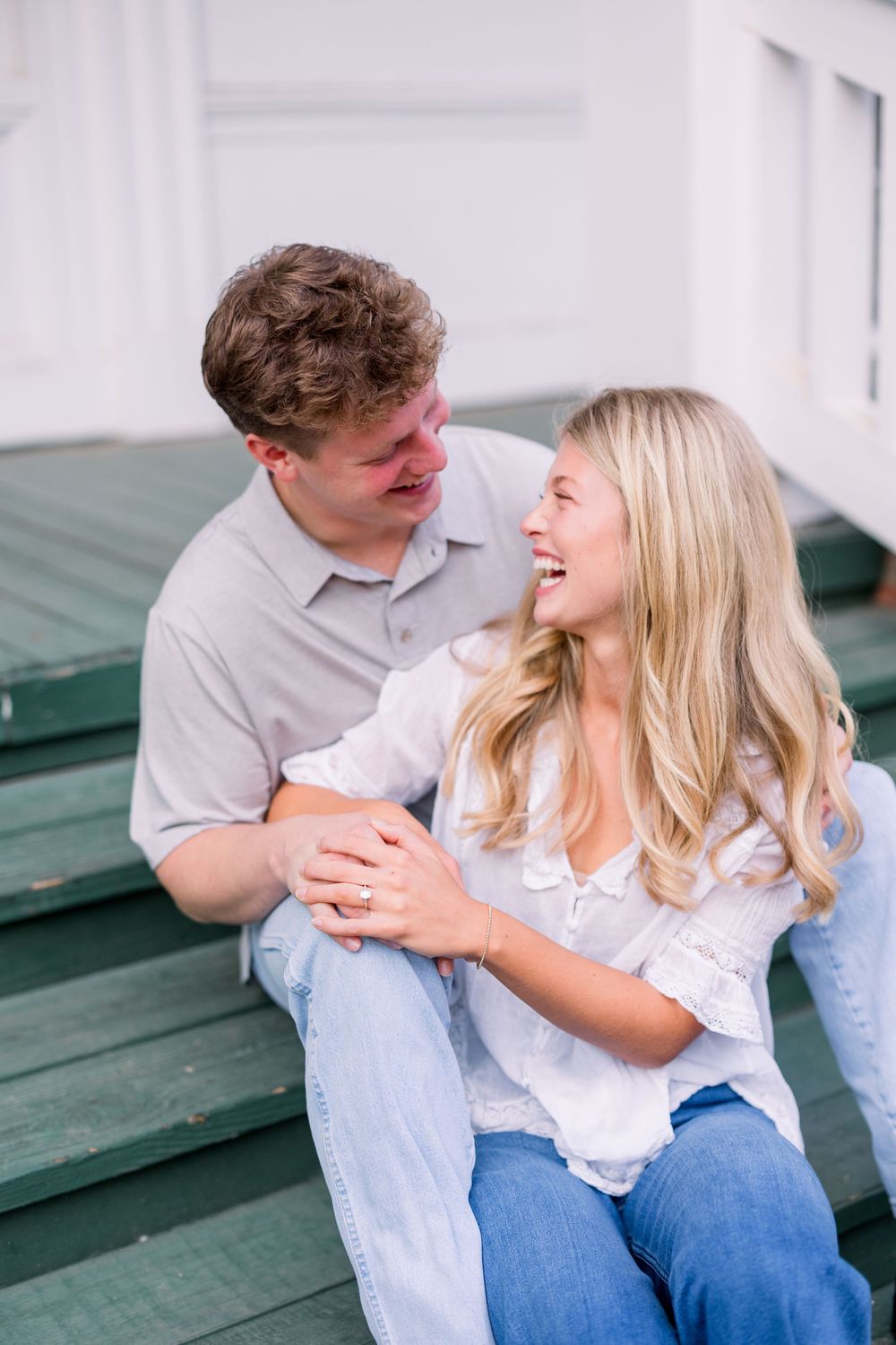 A couple shares a joyful moment while sitting together on green outdoor steps.