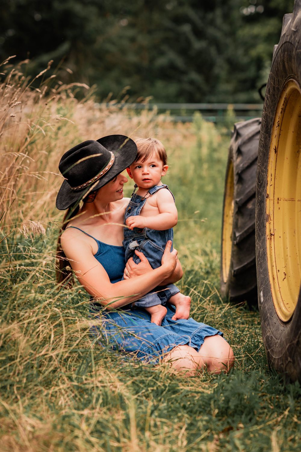 Family photography session capturing a mother and young son near a tractor on a farm in Uxbridge, Ontario.