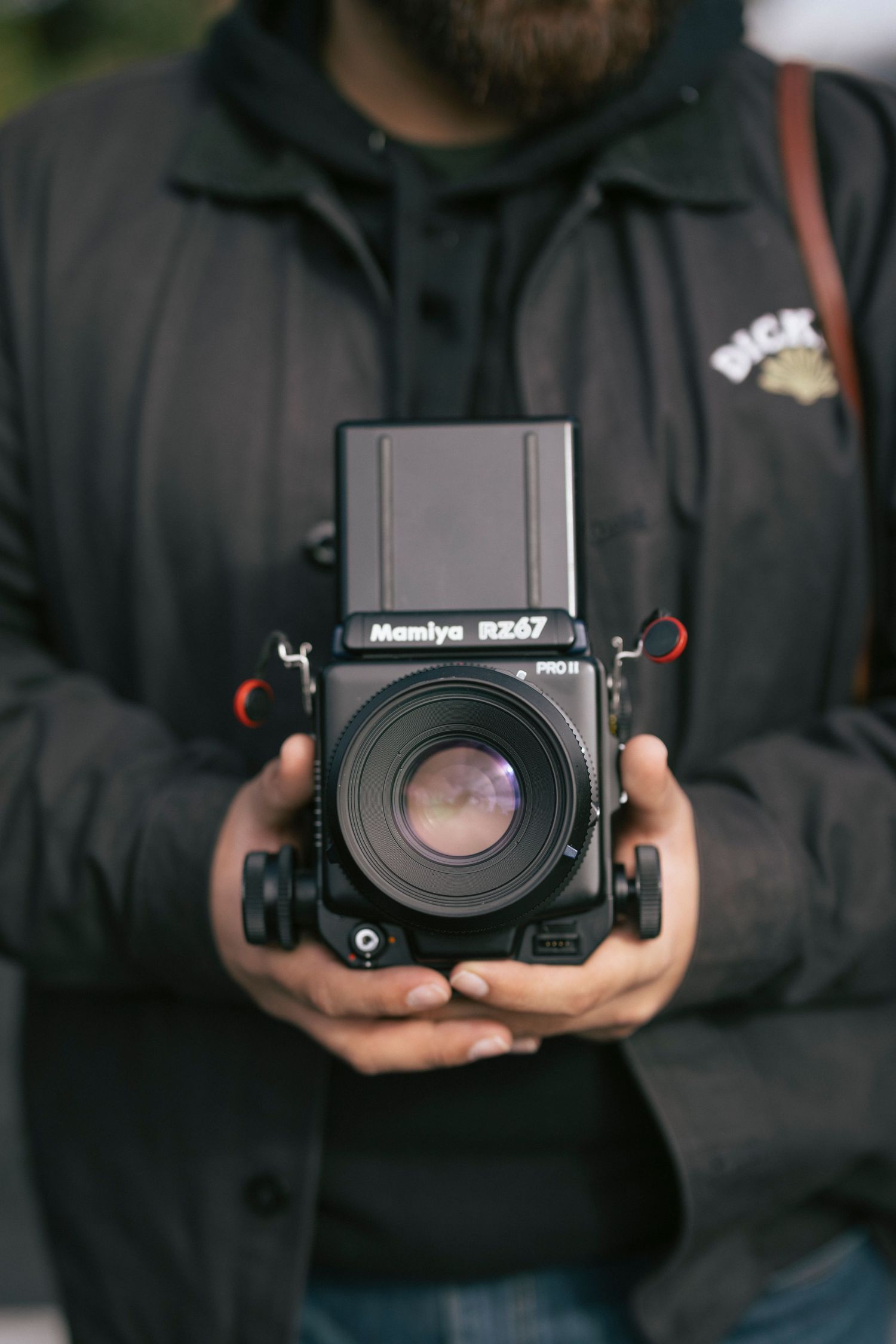 A sequence of shots showing hands holding a black Mamiya medium format camera from different angles.