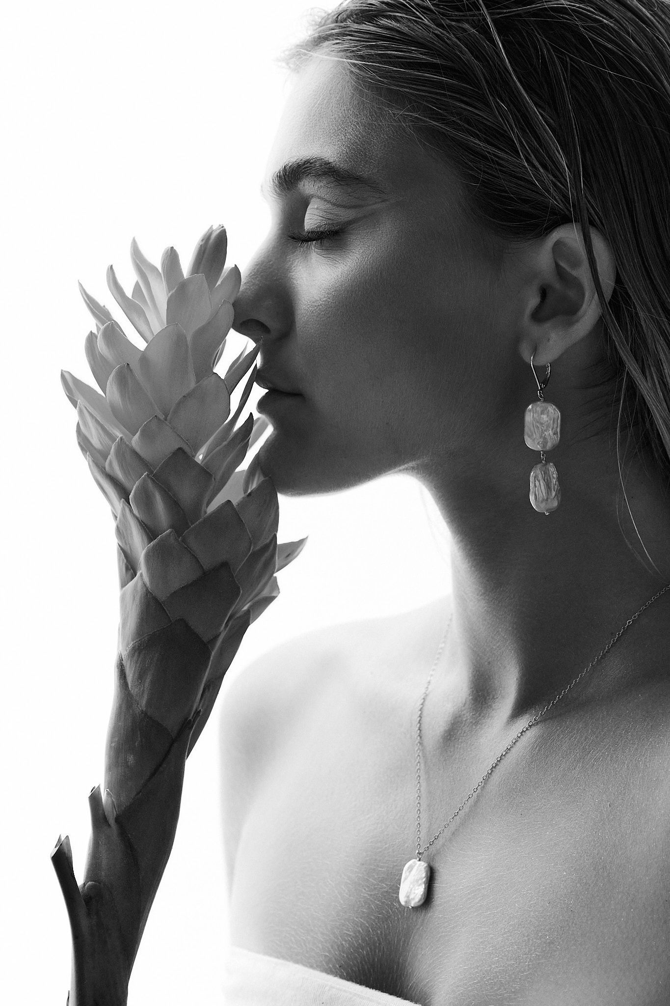 A black and white artistic portrait series showing a delicate lotus flower held against a silhouetted profile.