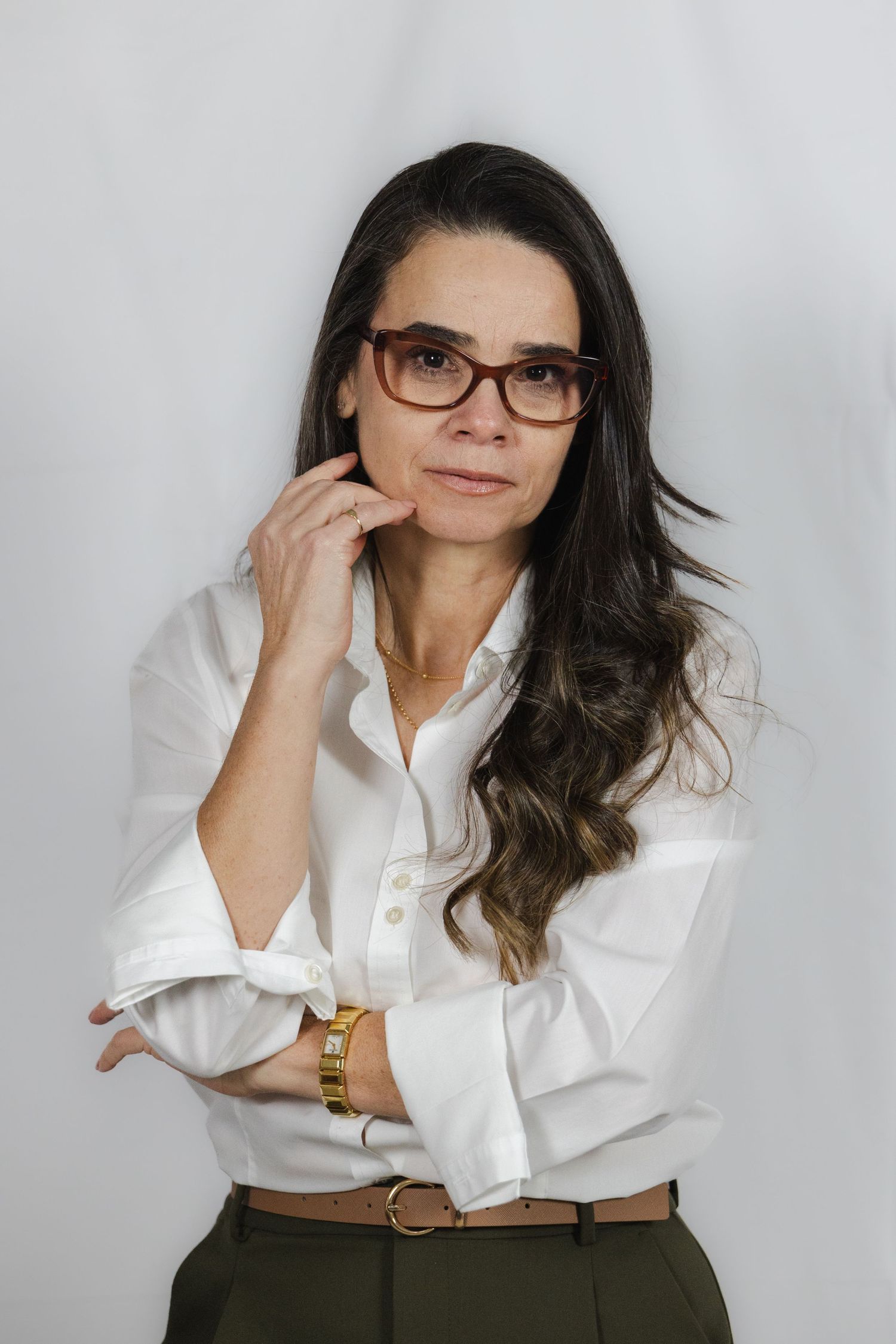 A person in a crisp white button-down shirt and dark skirt poses against a light background in a series of photos.