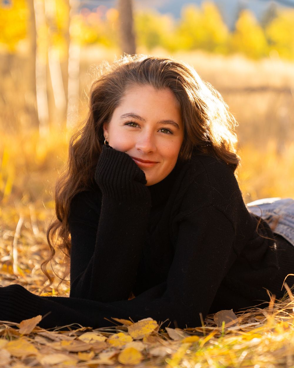 Autumn portrait session in fallen yellow leaves with warm golden light.